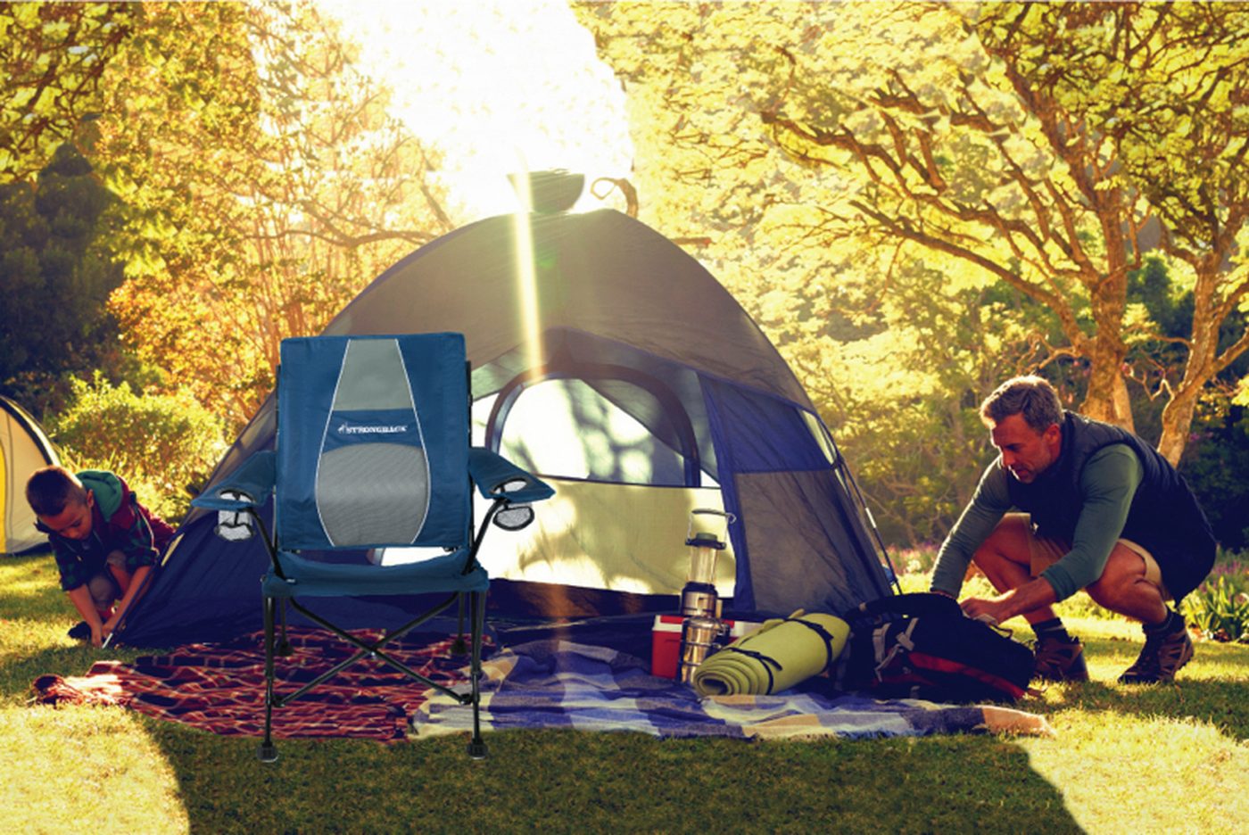 Zwei Personen bauen ein Zelt beim Campingausflug auf, mit dem Campingstuhl im Vordergrund